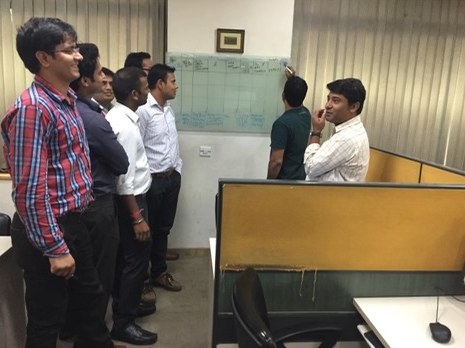 A Damco team gathered around a whiteboard planning their work