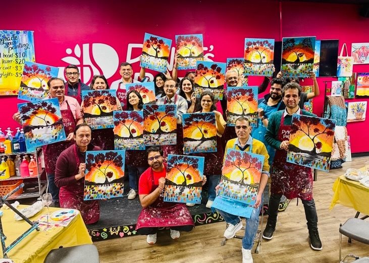 Damco's US team holding up their paintings after a Paint and Sip workshop