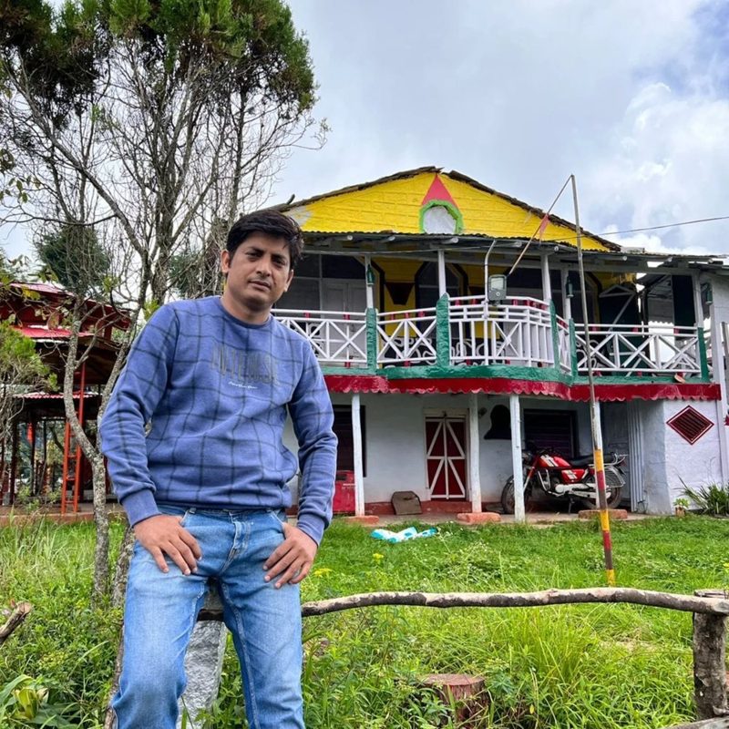 Devinder Singh Rawat outside a hillside house